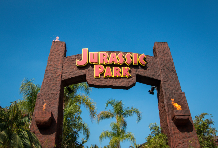 A big sign on the large gate entrance to Jurassic Park. 