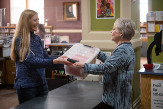 Person checking out book club kit at RIPL front desk