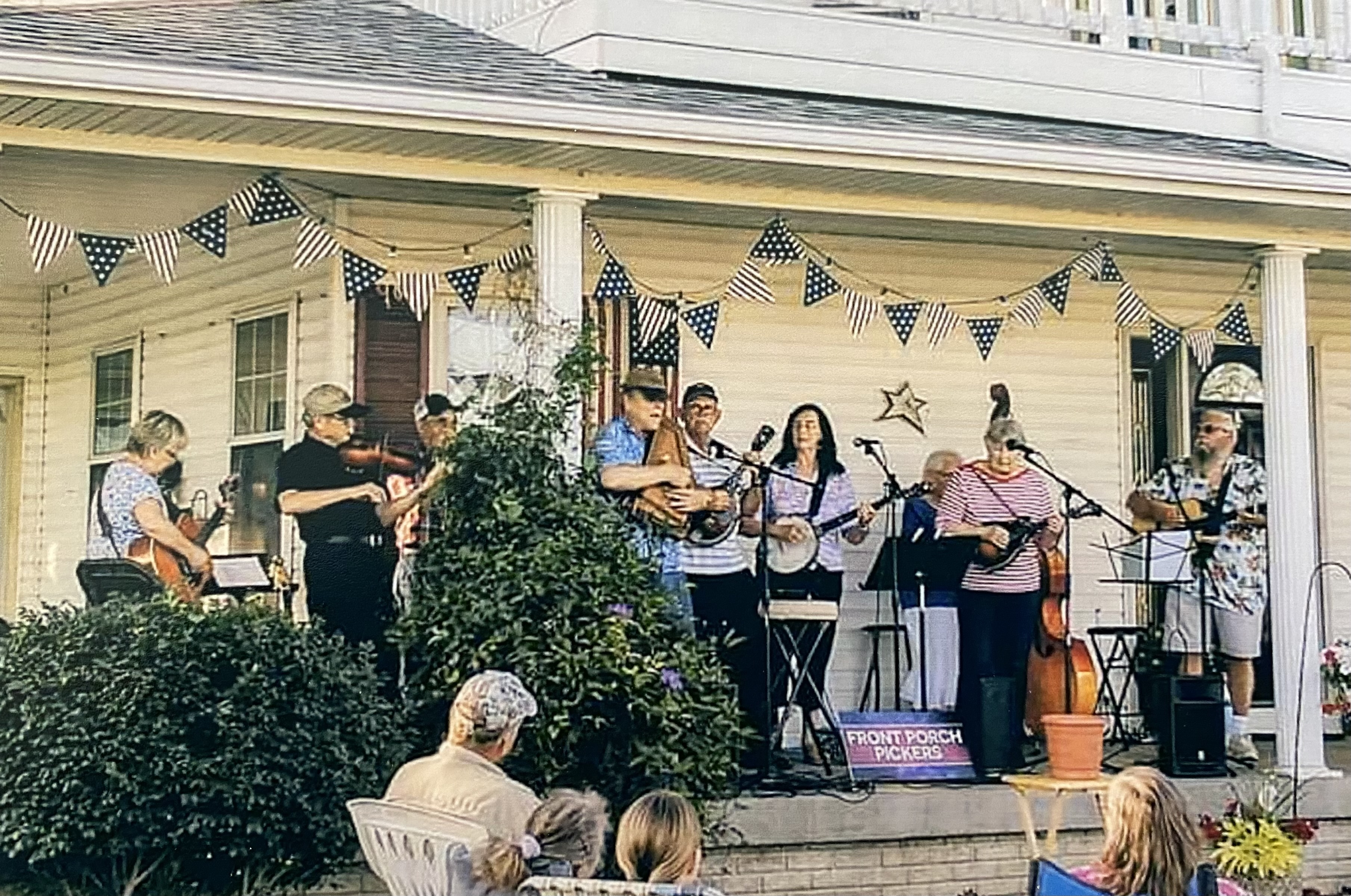 People playing musical instruments on a front porch.