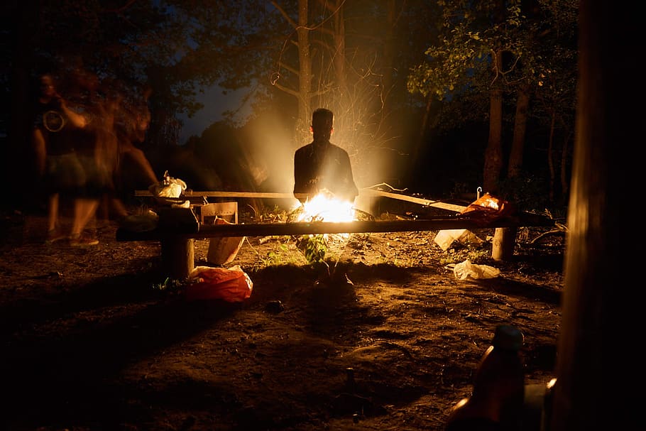 A picture of a campfire, which illuminates the ghostly figure of a man. 