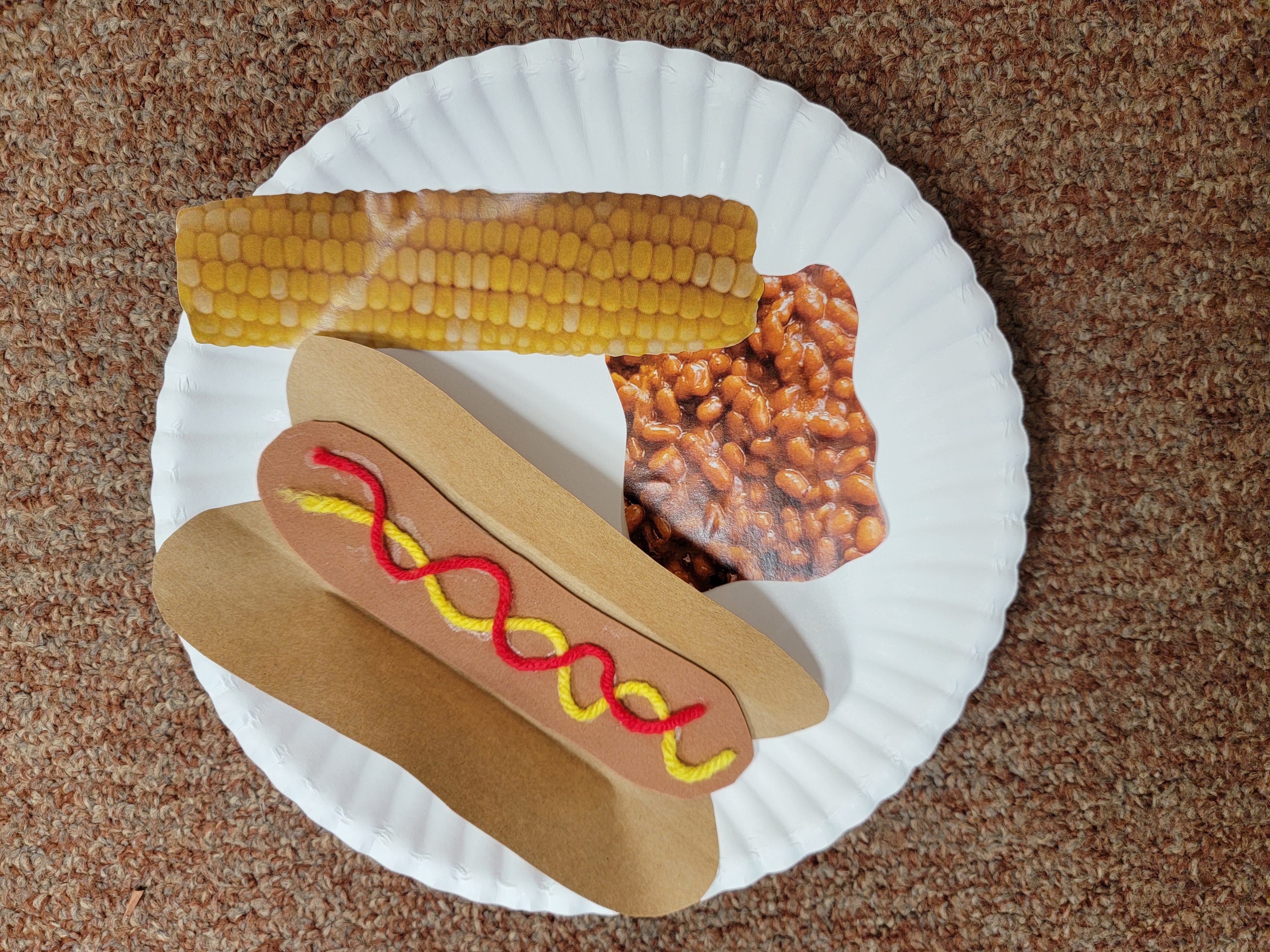 Hot dog, corn on the cob and beans on a plate 