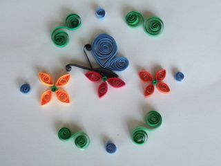 Paper quilling example including flowers and a butterfly.