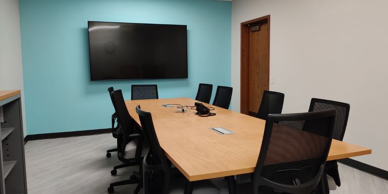 Photo of Watts-Midtown conference room. (Table surrounded by chairs, white and blue walls.)