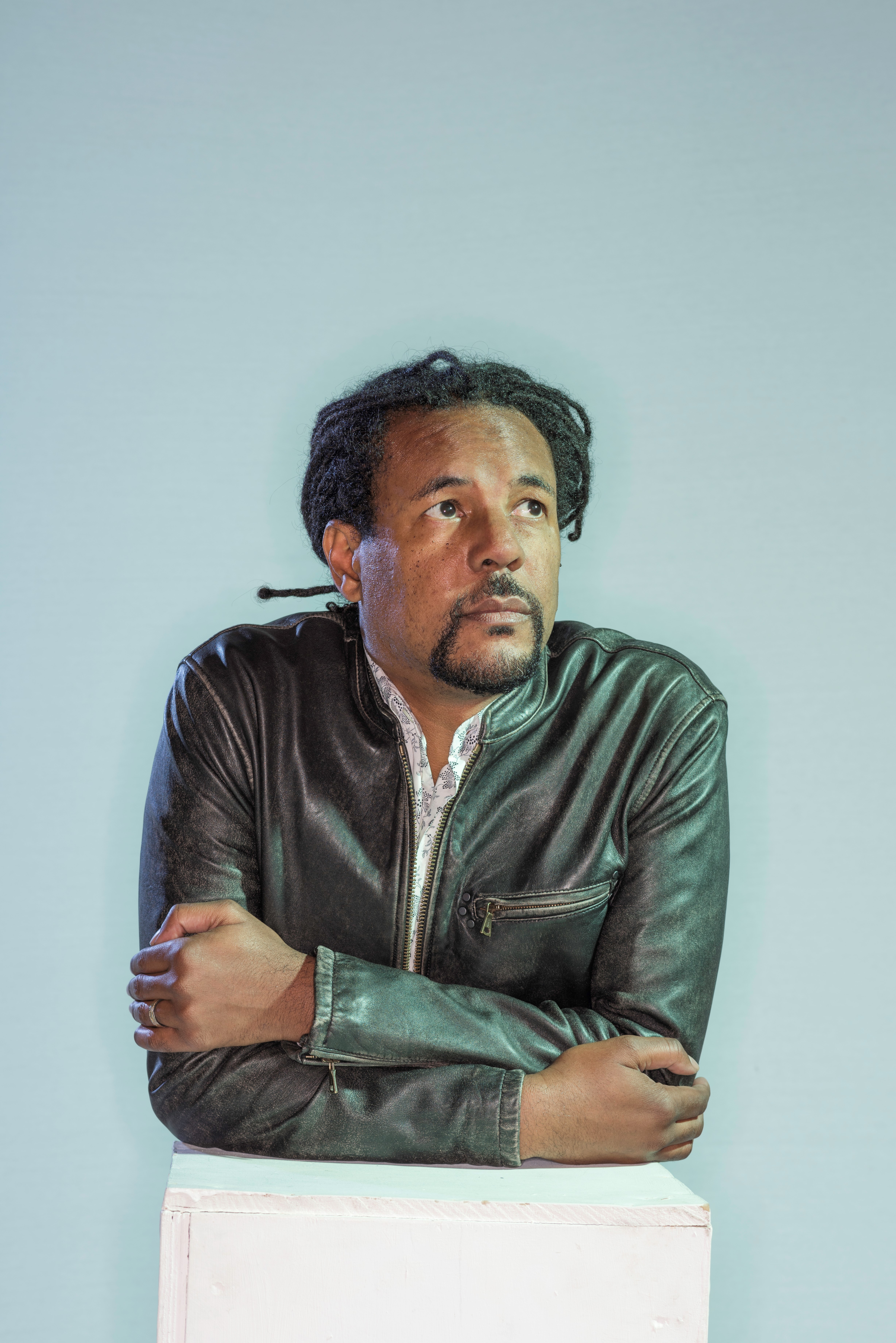 Author Colson Whitehead arms resting on podium, looking up and off to right