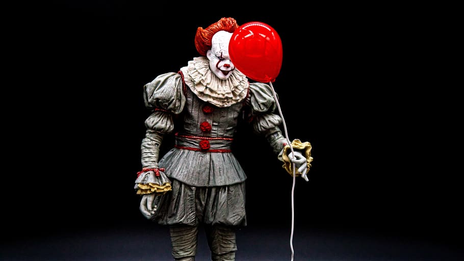 An action figure of Pennywise the clown (holding a red balloon) is pictured against a black background.
