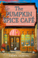 Book cover with black and white text reading "The Pumpkin Spice Café" by Laurie Gilmore, featuring a cozy storefront adorned with fall decorations