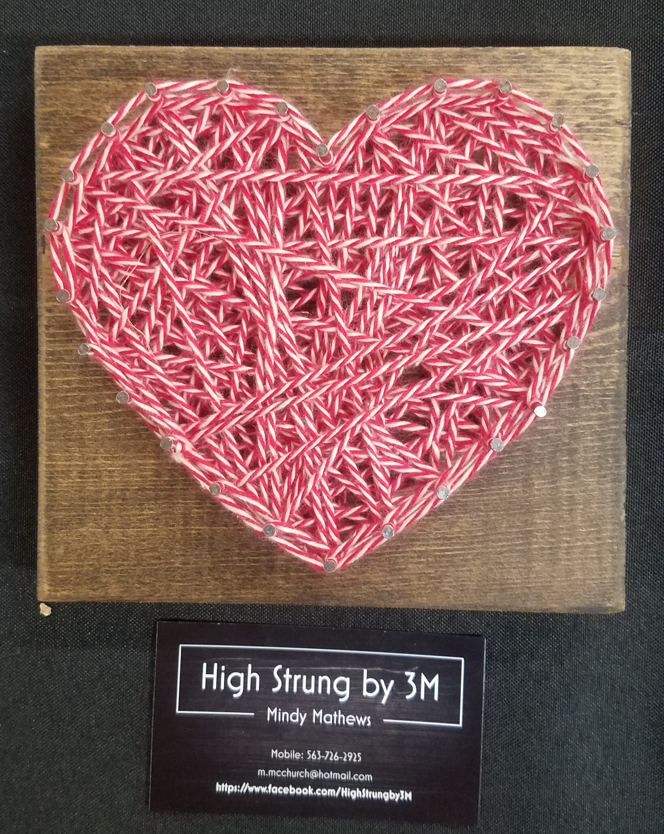 Heart formed of pink string wrapped around pegs