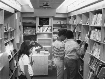 Black and white photo of children browsing shelves inside bookmobile