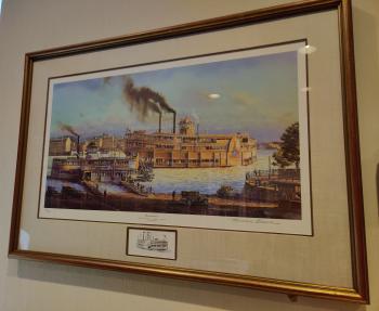 Framed print showing one small docked steamboat and a larger one in the river