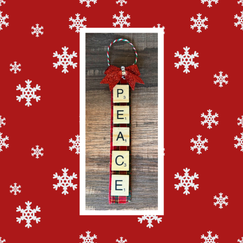 Photo of letter tile ornament craft against a red background with white snowflakes
