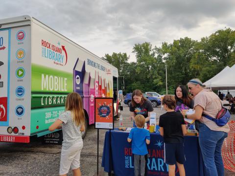 Staff working table at the Greek Fest next to Library2Go bookmobile