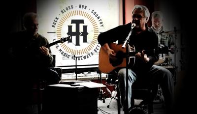 Shadowy image of men singing and playing guitar