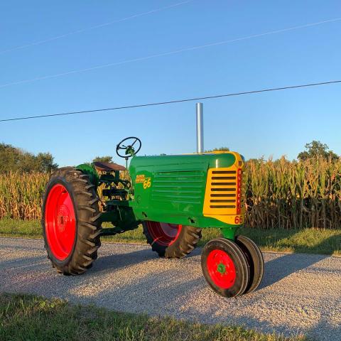 Oliver brand tractor on gravel road in front of a corn field