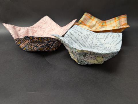 Three fabric bowls; one in blue, one pink, and one orange.