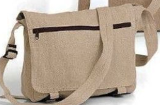 A tan bag with a zipper pocket on the front flap sits with the bag strap draped on top.