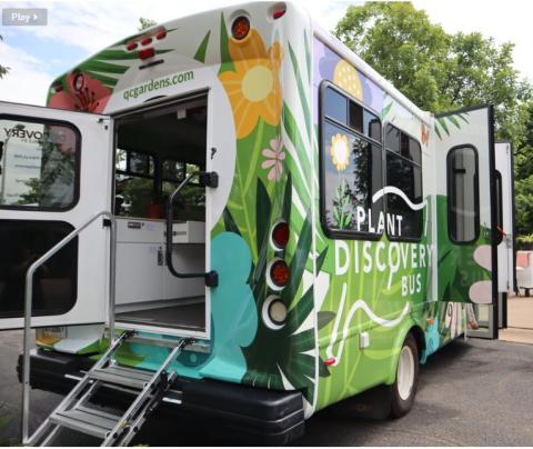 Colorful green bus decorated with flowers, back door open with steps extended.