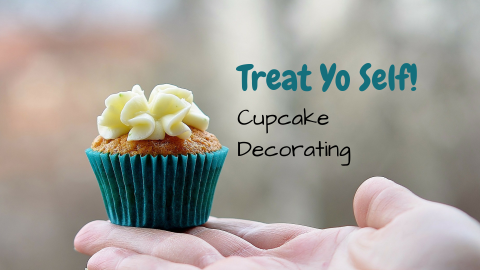Photo of hand holding out a frosted cupcake with words Treat Yo Self Cupcake Decorating