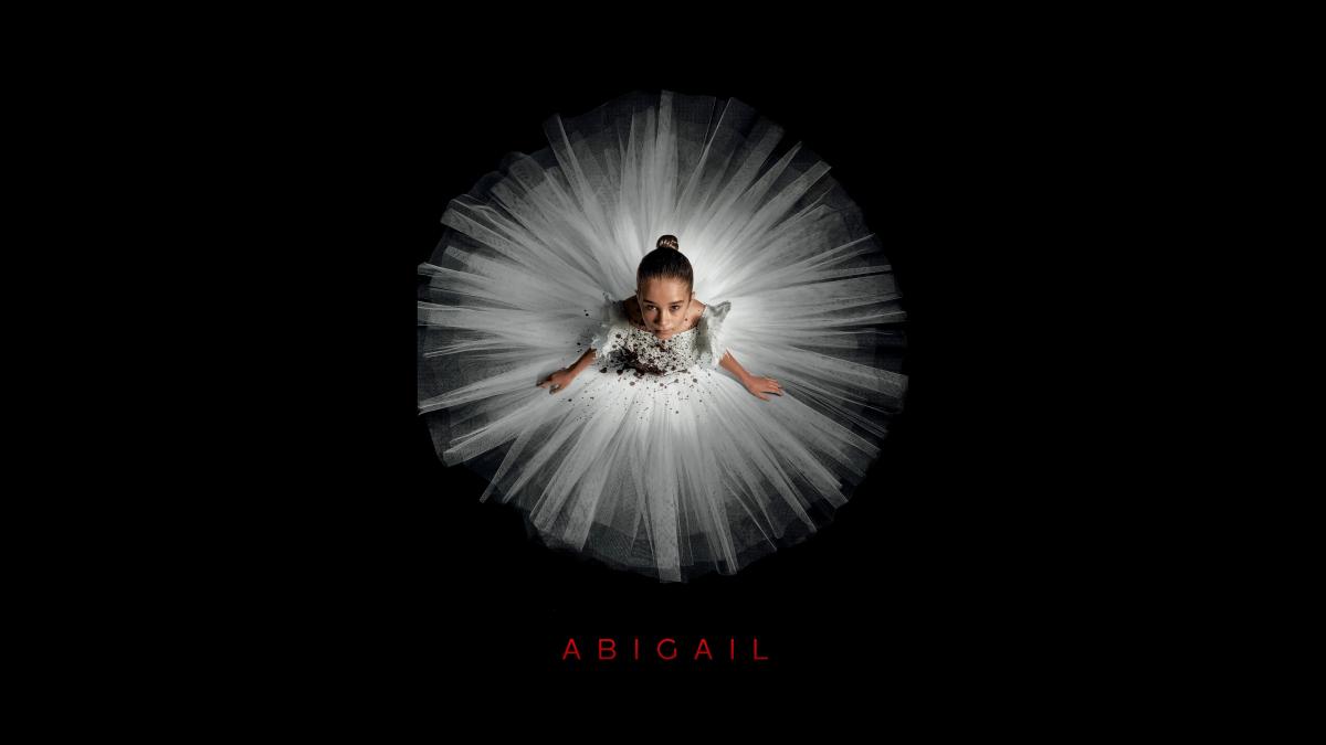 An image of Abigail, wearing a white tutu and sitting on a black background.
