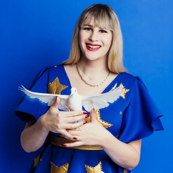 Mikayla Oz in a blue dress holding a bird 